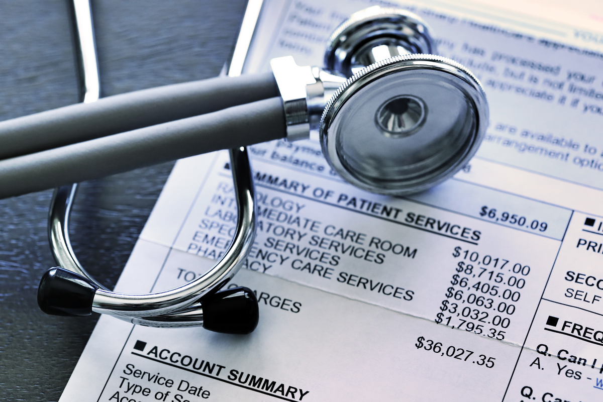 A closeup of a medical bill with a stethoscope resting on top of it.
