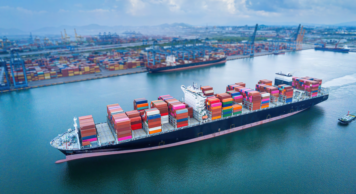 A barge carrying cargo heads away from a port.