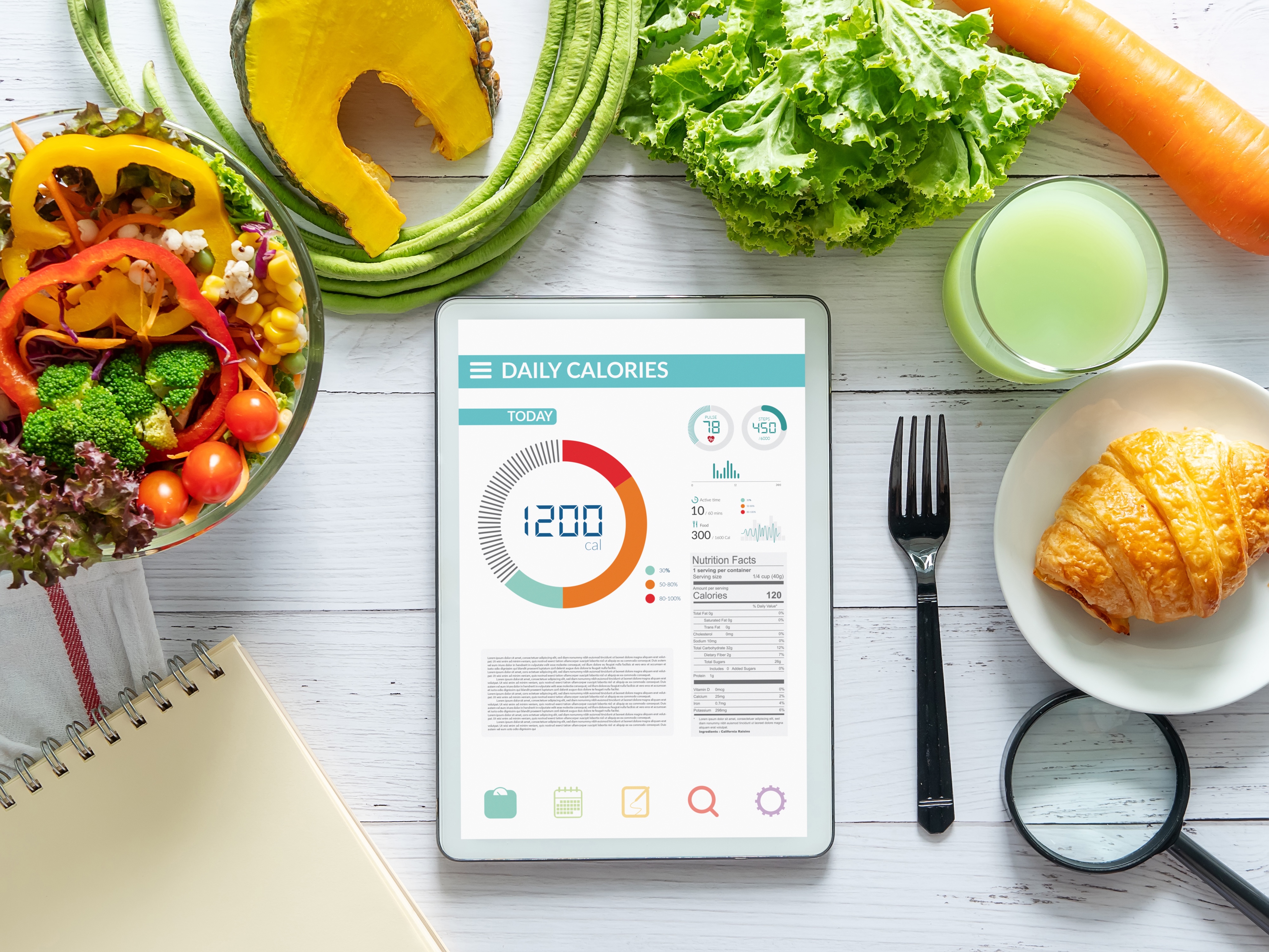 Daily calorie log on a tablet computer, surrounded by healthy food choices.