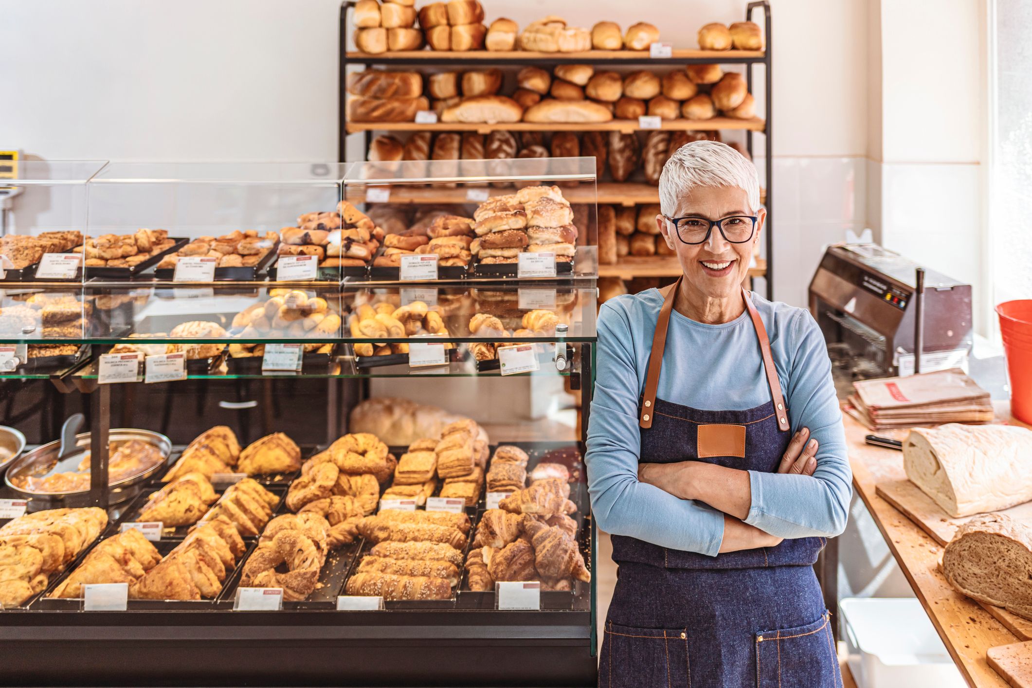 A person in an apron standing in a bakery.