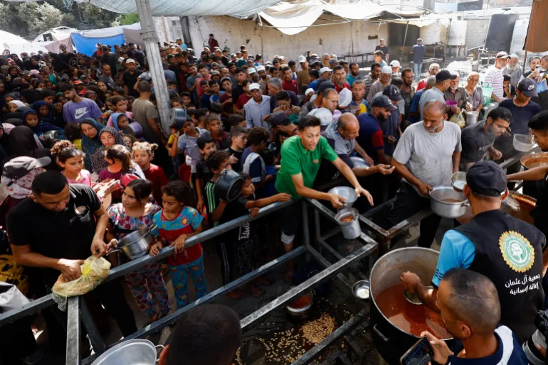 Palestinians gather to receive food from a charity kitchen, in Nuseirat, central Gaza Strip, October 7, 2025. REUTERS/Mahmoud Issa