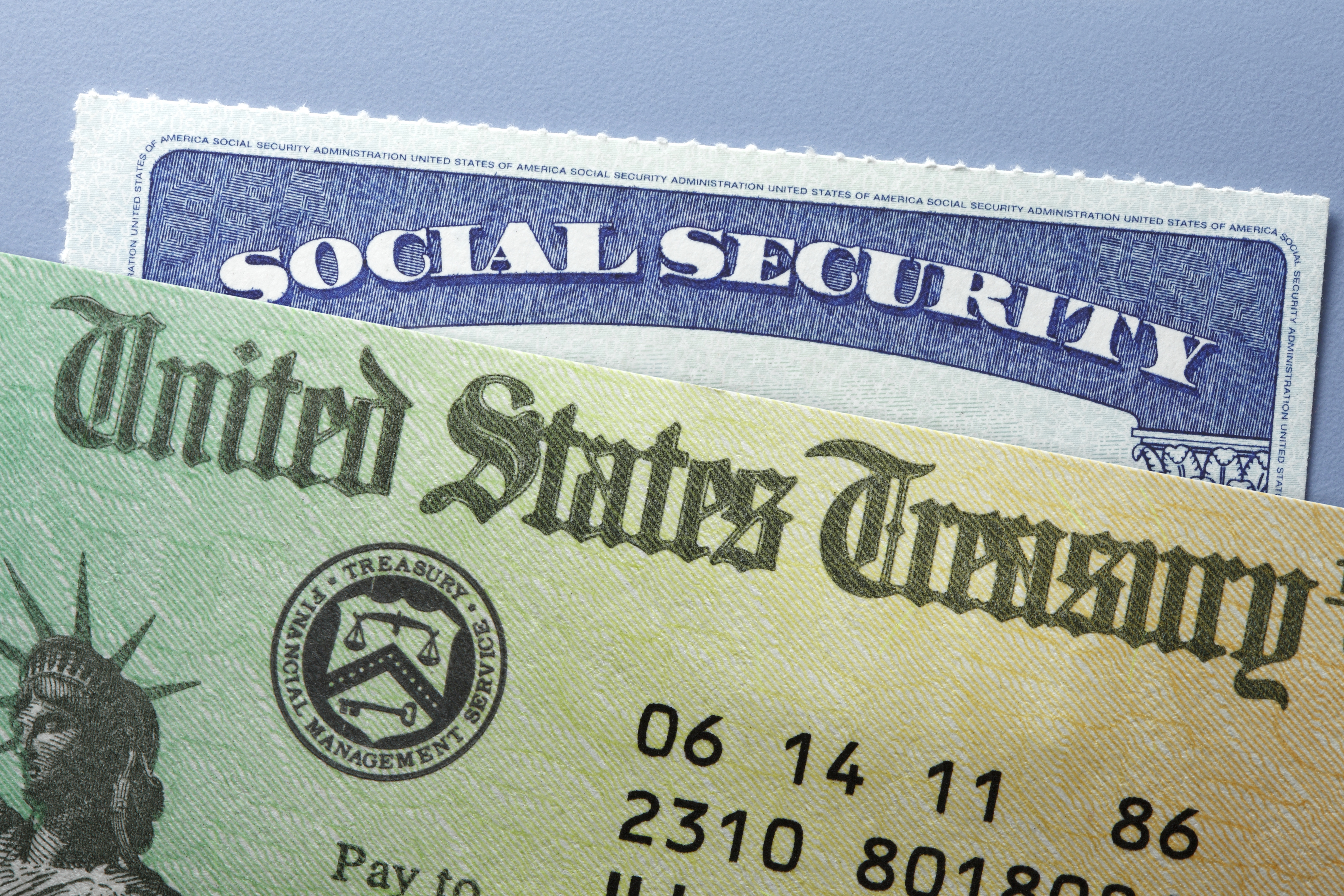 Top of a Social Security card peeking out from behind a U.S. Treasury check.