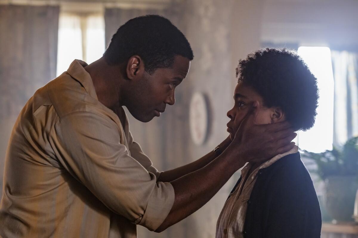 A man holds the face of a young girl who looks at her father in the eyes.