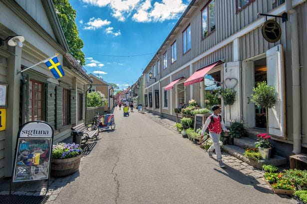 Sigtuna, Sweden – June 2, 2014: Young boy strolls the old main street in Sigtuna. Founded in 980 Sigtuna is the oldest city in Sweden. Sigtuna belongs to Stockhom County and the province of Uppland.