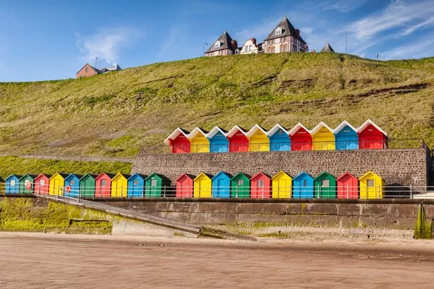 Rows of colorful beach huts on the promenade at Whitby Sands, Whitby, North Yorkshire