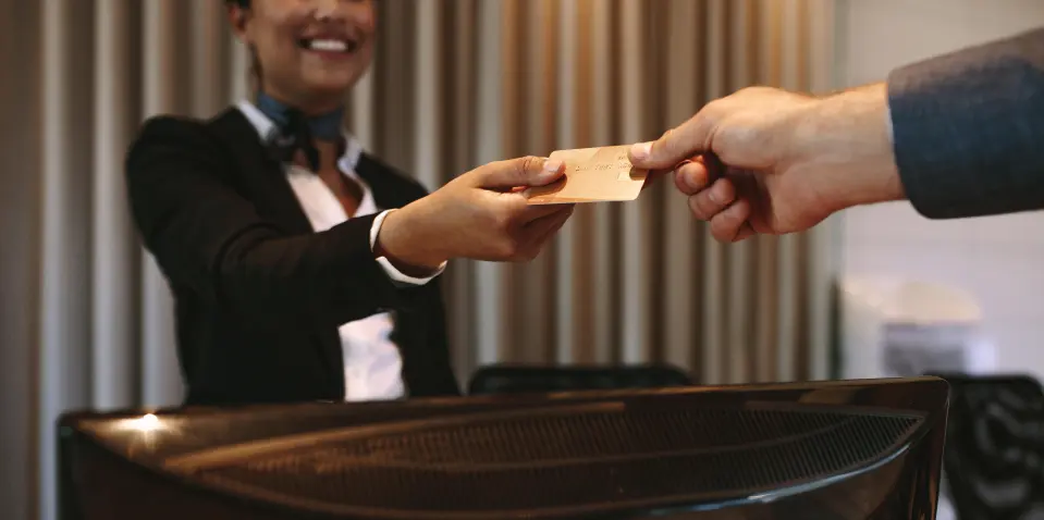 A businessman hands a credit card to a hotel receptionist.