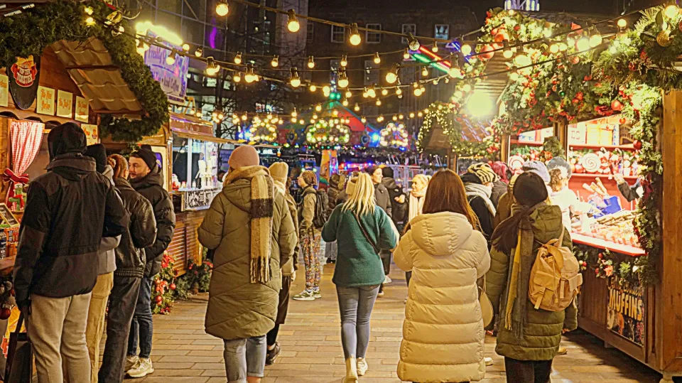 a group of people are walking through a christmas market