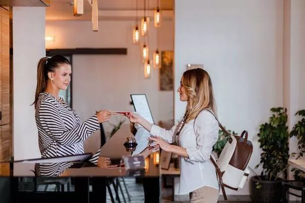 Receptionist assists guest with check-in process at a modern hotel lobby