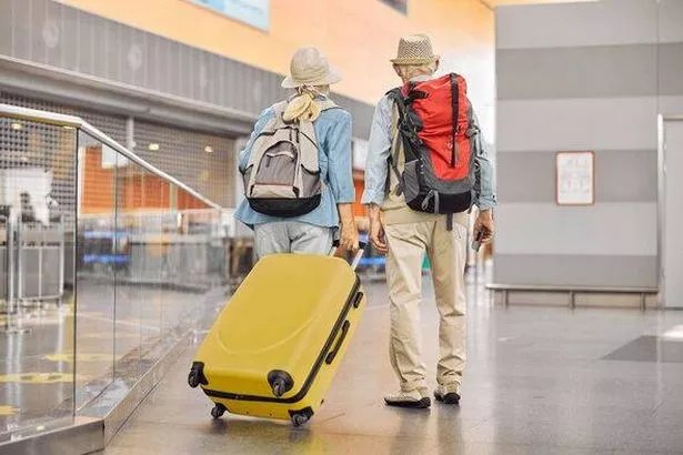 Two Caucasian elderly travelers standing at the airport
